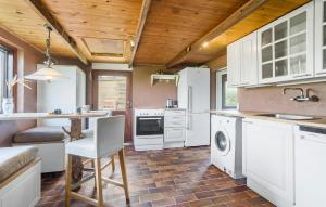a kitchen with white cabinets and a table and a chair at Cozy Home In Sandved With Wifi in Sandved