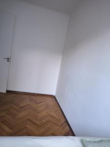 1 dormitorio con suelo de madera y pared blanca en Benito blanco, en Montevideo