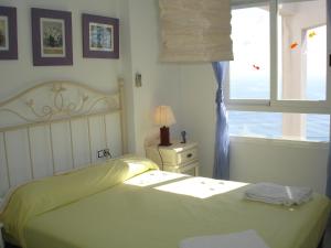 a white bedroom with a bed and a window at VillaMarina Apartments - Zand Properties in Benidorm