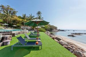 - une rangée de chaises longues et un parasol à côté de la piscine dans l'établissement ShaSa Resort - Luxury Beachfront Suites, à Lamai