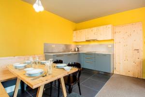 a kitchen with a wooden table and yellow walls at Apartmány Severák Smrk in Janov nad Nisou