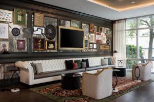 a living room with a couch and a tv on a wall at Hotel Tonnelle New Orleans, a Tribute Portfolio Hotel in New Orleans