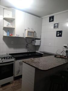 a kitchen with white cabinets and a counter top at Condomínio Buritis Centro de Bertioga a 100Mts da praia in Bertioga