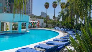a swimming pool with blue lounge chairs and palm trees at Holiday Inn Queretaro Zona Diamante by IHG in Querétaro