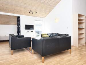 ein Wohnzimmer mit zwei schwarzen Sofas und einem TV in der Unterkunft 8 person holiday home in B rkop in Egeskov