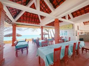 uma sala de jantar com mesas e cadeiras e o oceano em Sand Beach Resort em Mui Ne