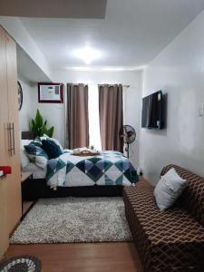 PY Suites Tagaytay في تاجيتاي: غرفة نوم بسرير واريكة