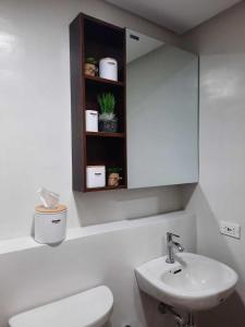 PY Suites Tagaytay في تاجيتاي: حمام مع حوض ومرحاض ومرآة