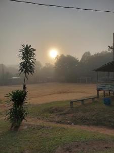 un parque con un banco y el sol en el fondo en Quarto compartilhado e camping na floresta, en Manaus