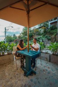 Ein Mann und eine Frau, die an einem Tisch unter einem Schirm sitzen in der Unterkunft Cocli Hotel Boutique Salento in Salento