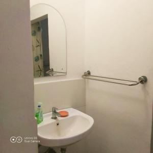 a white bathroom with a sink and a mirror at PM Room in Jakarta