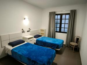 Habitación con 2 camas, silla y ventana en Turina House - 3 habitaciones, en Las Palmas de Gran Canaria