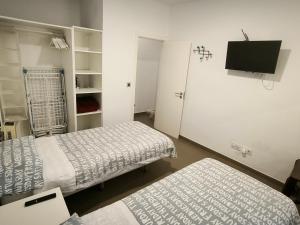 ラスパルマス・デ・グランカナリアにあるTurina House - 3 habitacionesのベッド2台、薄型テレビが備わる客室です。