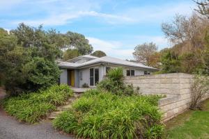 a house with a retaining wall and a fence at Sky Mirror Cottage in Rhyll