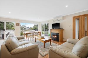 a living room with two couches and a fireplace at Sky Mirror Cottage in Rhyll