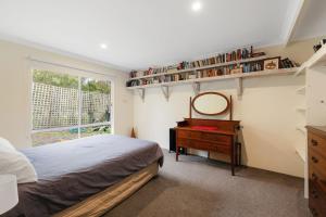 a bedroom with a bed and a mirror and a dresser at Sky Mirror Cottage in Rhyll