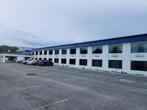 un gran edificio blanco con coches aparcados en un aparcamiento en Motel 6 Williamstown, WV, en Williamstown