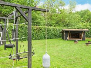 a swing in a yard with a dog house at 8 person holiday home in Juelsminde in Sønderby