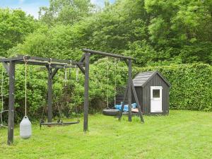 a playground with swings and a play house at 8 person holiday home in Juelsminde in Sønderby