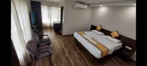a hotel room with a bed and two chairs at Hotel Aiba Regency in Coimbatore
