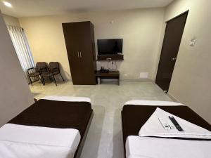 a hotel room with two beds and a flat screen tv at Hotel Aiba Regency in Coimbatore