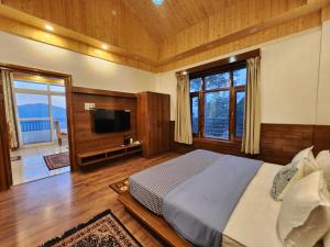 1 dormitorio con 1 cama grande y TV en The Morel House - A Forest Retreat, en Nārkanda