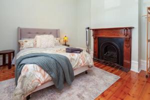 1 dormitorio con 1 cama y chimenea en Stanley Stay - Adelaide 3 Bdrm, Central Location, WiFi, en Woodville
