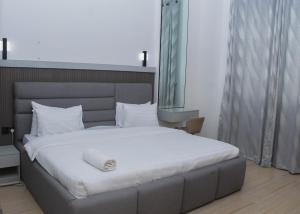 um quarto com uma cama grande e lençóis brancos em Margi Homes em Apapa Eleko