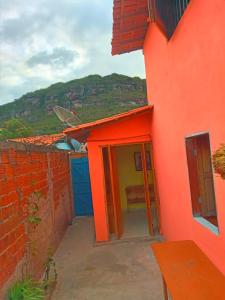 um edifício laranja com uma porta aberta com um banco em Casa Rainha da Serra em Mucugê