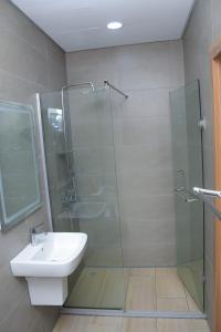 uma casa de banho com uma cabina de duche em vidro e um lavatório. em Margi Homes em Apapa Eleko