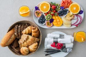 チャウエンノイビーチにあるPanoramic Duplex Studioの朝食の食べ物と果物が載った2枚の皿が置かれたテーブル