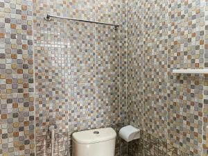 un bagno con wc e parete piastrellata di Ruma Kaca Simanindo Bed&Breakfast ad Ambarita