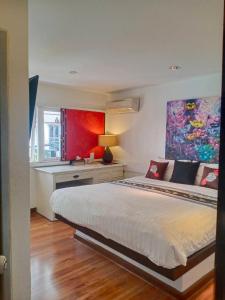 a bedroom with a bed with a desk and a painting at Baipho Lifestyle in Patong Beach
