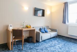 a living room with a couch and a table and a desk at Hotel am Fjord in Flensburg