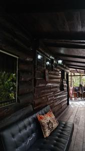 un sofá de cuero en el porche de una cabaña de madera en Cabaña entre orquídeas en Valle de Ángeles