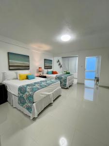 Duas camas num quarto grande com pisos brancos em Posada Centric Studio Isla Verde em San Juan
