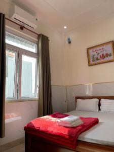 a bedroom with a bed with a window and a red blanket at Phú Gia Hotel Bảo Lộc in Bao Loc