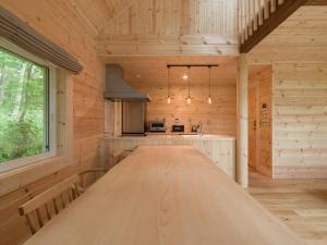 山中湖的住宿－[lamp. Yamanaka] 新築高級デザイナーズ ログハウス 大自然の中でBBQ可！，小木屋内厨房里一张大木桌