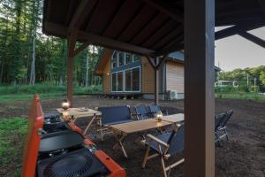山中湖村にあるlamp yamanaka-Private Villa for Up to 10 Guests, Free BBQ, Baby-Friendly, 5-Min Drive from Lake Yamanaka, 20-Min Drive from Lake Kawaguchiのテーブルと椅子が備わるパビリオンの下に駐輪するオートバイ