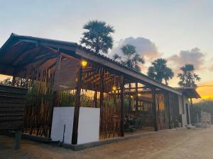 un petit bâtiment avec des palmiers en arrière-plan dans l'établissement Borassus Nature Huts, à Jaffna