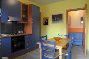 une cuisine avec une table en bois et des chaises bleues dans l'établissement Hotel Blumentag, à Paola