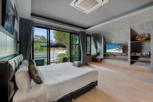a bedroom with a large bed and a large window at Samui Fishing Club and Resort in Na Mueang