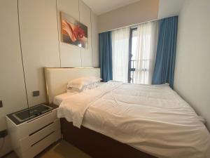Schlafzimmer mit einem weißen Bett und einem Spiegel in der Unterkunft Ruby’s in Bao'an