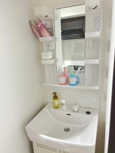 uma casa de banho com um lavatório branco e um espelho. em 303 Oshiage sta 3mins walk! Wi-Fi & Elevator 4pax em Tóquio