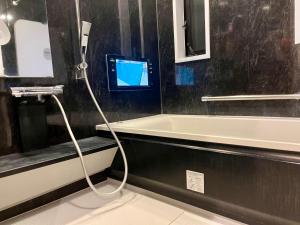 a bathroom with a bath tub and a tv on the wall at Ikebukuro house with 3BR Shinjuku 5min in Tokyo