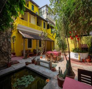 ein gelbes Haus mit einem Teich, einem Tisch und Stühlen in der Unterkunft Luigi Villa in Puducherry