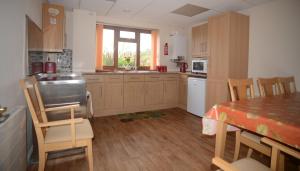 a kitchen with wooden cabinets and a table with chairs at Summerfield Farm in Tilbrook