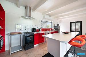 a kitchen with red cabinets and a counter top at Maison de Rose in Auckland