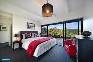 a bedroom with a large bed and a red chair at Maison de Rose in Auckland