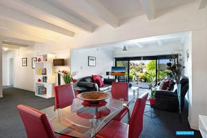 een woonkamer met een glazen tafel en rode stoelen bij Maison de Rose in Auckland